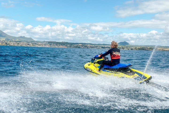 a man riding on the back of a boat in a body of water