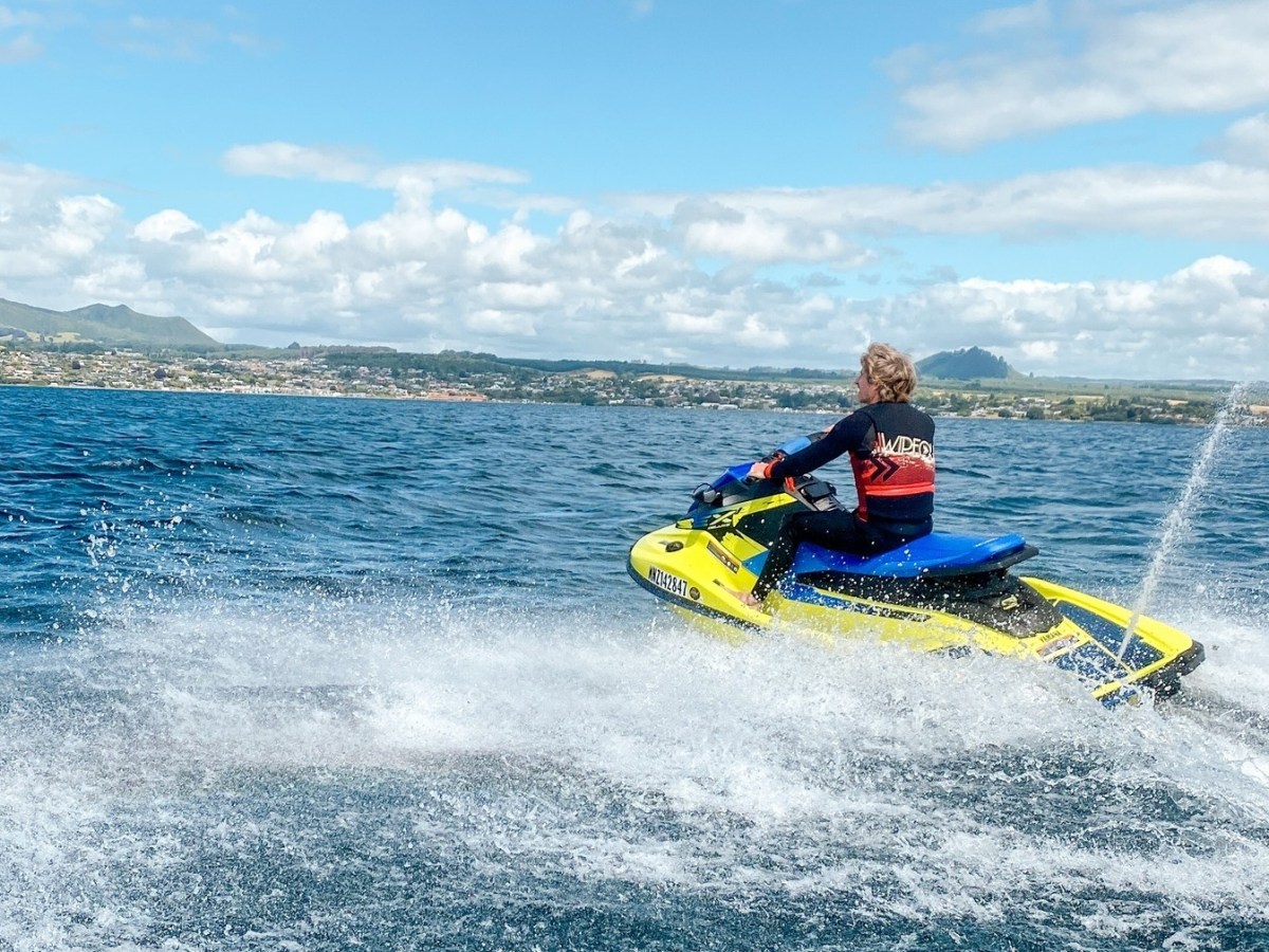 a man riding on the back of a boat in a body of water